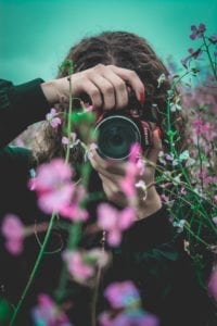 Female shooting photos through purple flowers