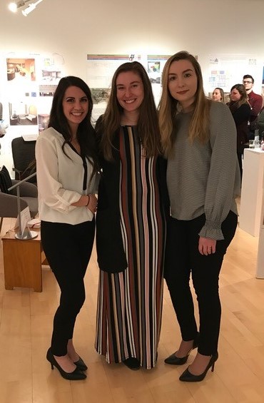 Three women standing in an art gallery smiling 