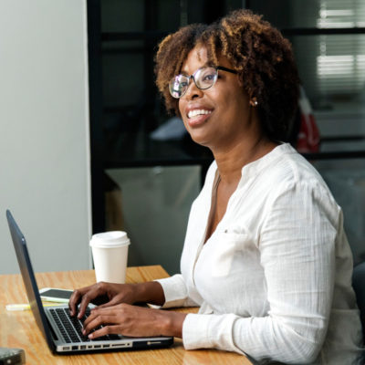 Flexible Business Bottom Image woman looks up and smiles while working on a laptop
