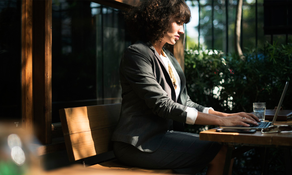 woman working on a laptop outside at a restaurant