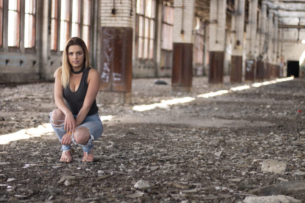 women crouching in an abandoned building with a gravel floor